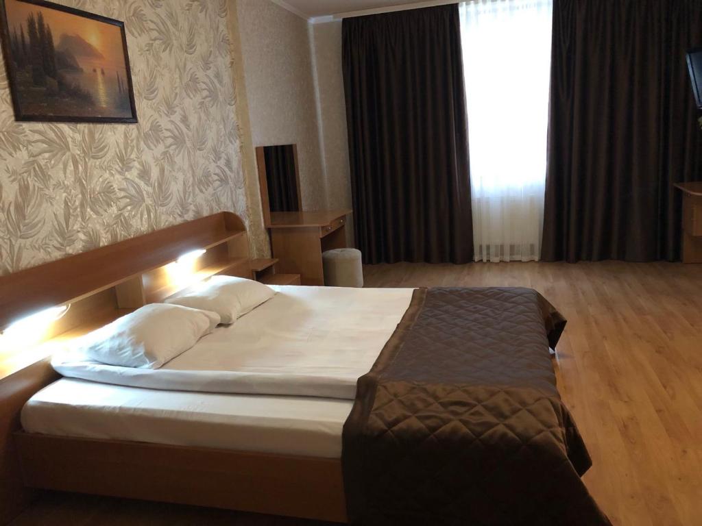 Comfort Hotel في كييف: غرفة نوم مع سرير كبير مع إضاءة عليه
