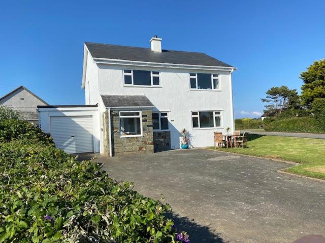 a large white house with a patio and a yard at Deu Draeth in Abersoch