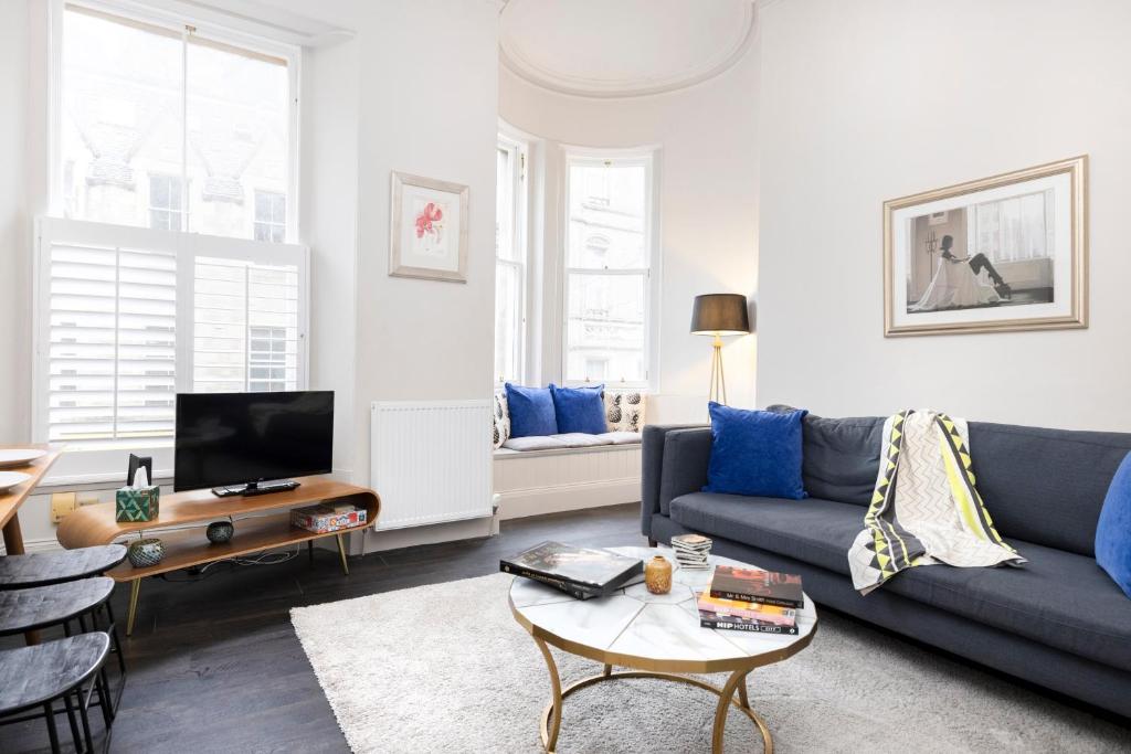 a living room with a blue couch and a table at ALTIDO Sophisticated and Bright 4BR apt near Edinburgh Castle in Edinburgh