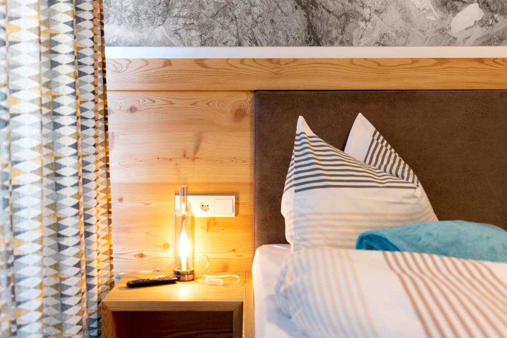 a bed with a nightstand with a lamp on a table at Noreia Pitla in Ortisei