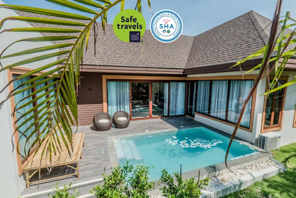 a villa with a swimming pool in front of a house at Triple Tree Beach Resort in Cha Am