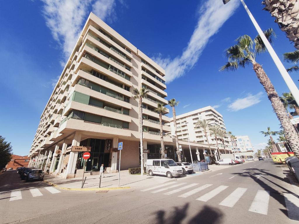 a large building on a city street with palm trees at Patacona Green Holiday in Valencia