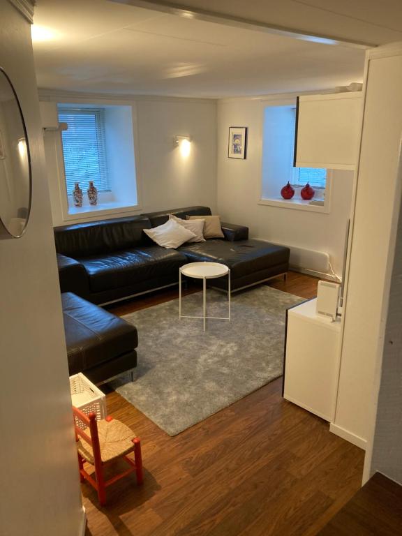 a living room with a black couch and a table at Kjellerleilighet - nært Haukeland sykehus. in Bergen