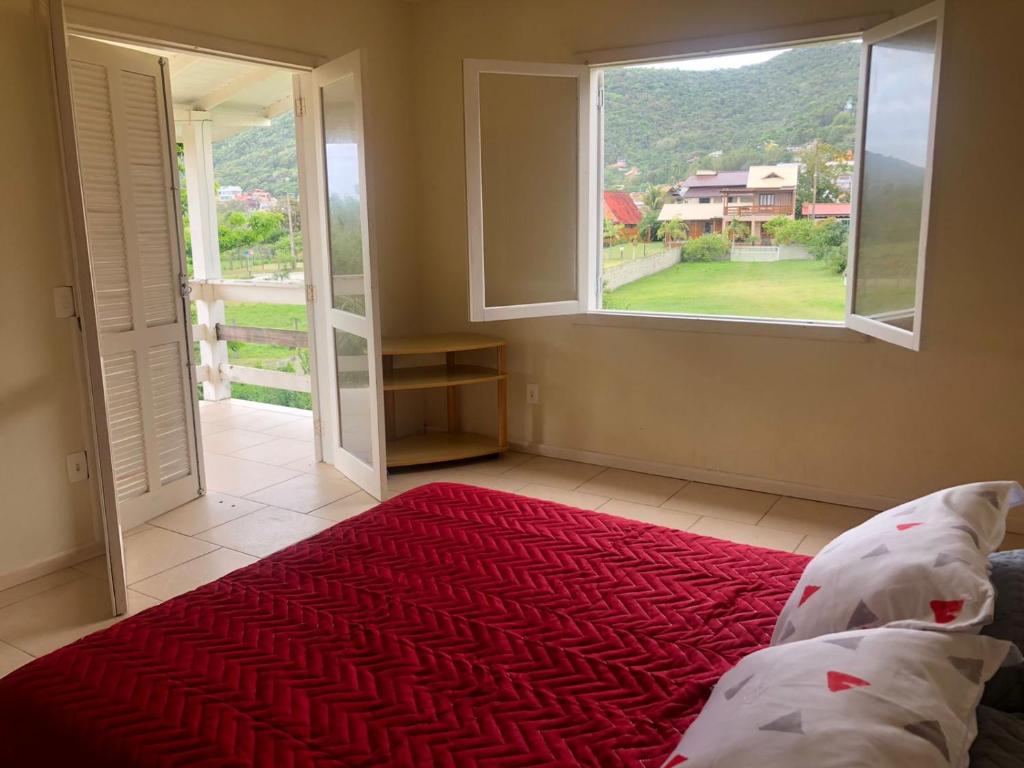 a bedroom with a bed and a large window at Casa grande na Gamboa Garopaba in Garopaba