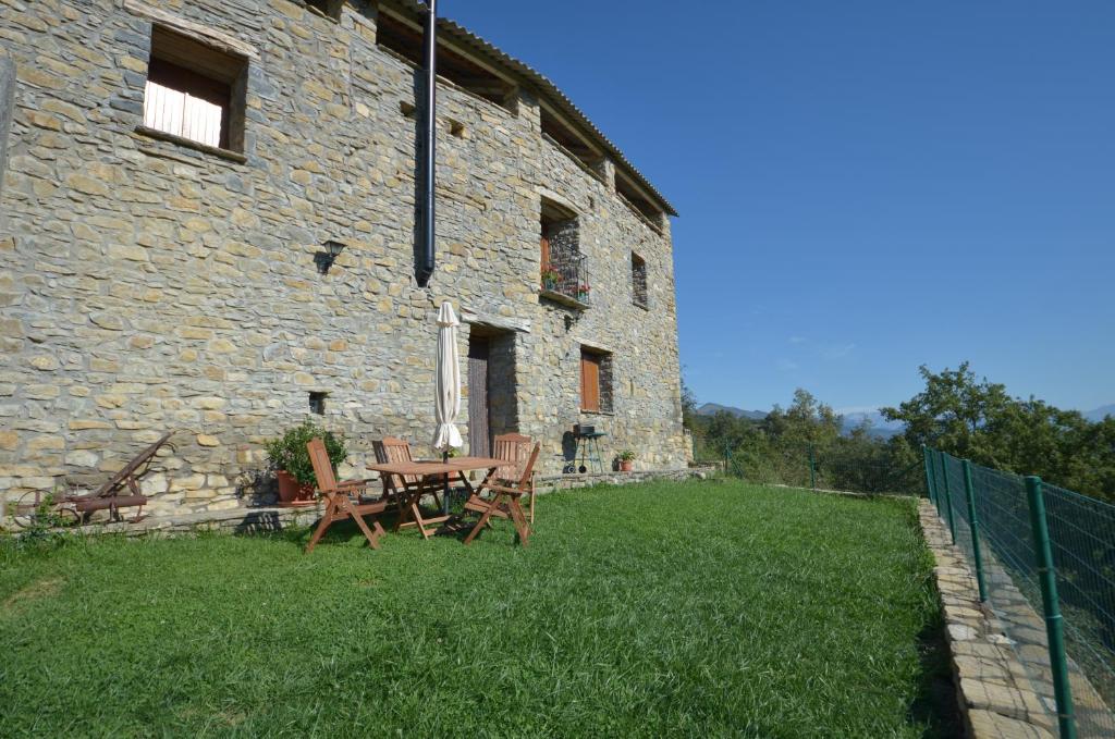Casa Rural Urbe في Campodarbe: طاولة وكراسي أمام مبنى حجري