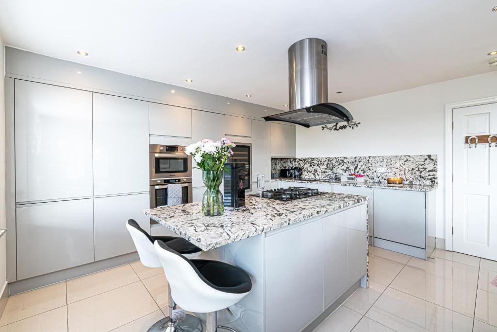 a kitchen with white cabinets and a vase of flowers on a counter at The POPULAR Chester Racecourse Apartments, Sleeps 4, FREE Parking in Chester