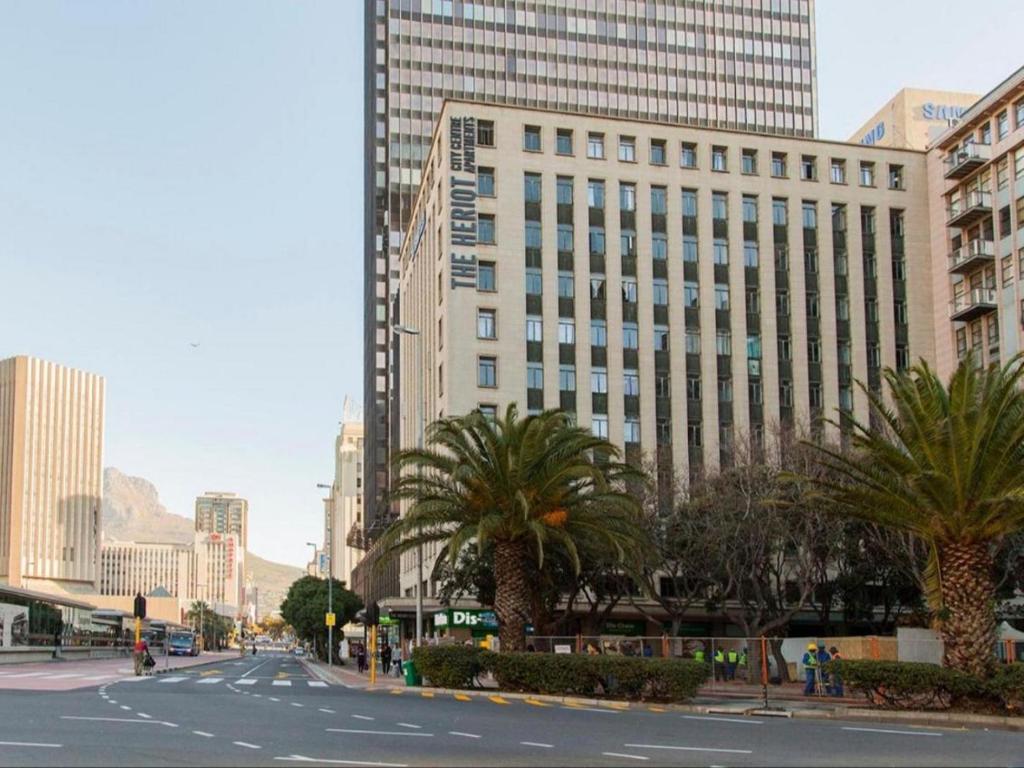 una calle urbana vacía con palmeras y edificios en The Heriot City Centre Apartments, en Ciudad del Cabo