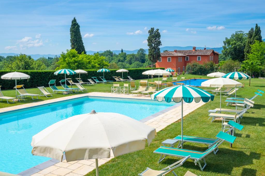 a swimming pool with chairs and umbrellas and a group at Tenuta di Rota in Reggello