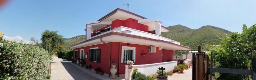a red and white house with mountains in the background at Valeri 's Country House in Sperlonga