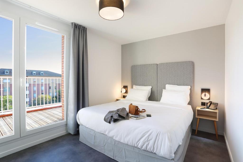- une chambre avec un lit et une grande fenêtre dans l&#39;établissement Odalys City Toulouse Centre Compans Caffarelli, à Toulouse