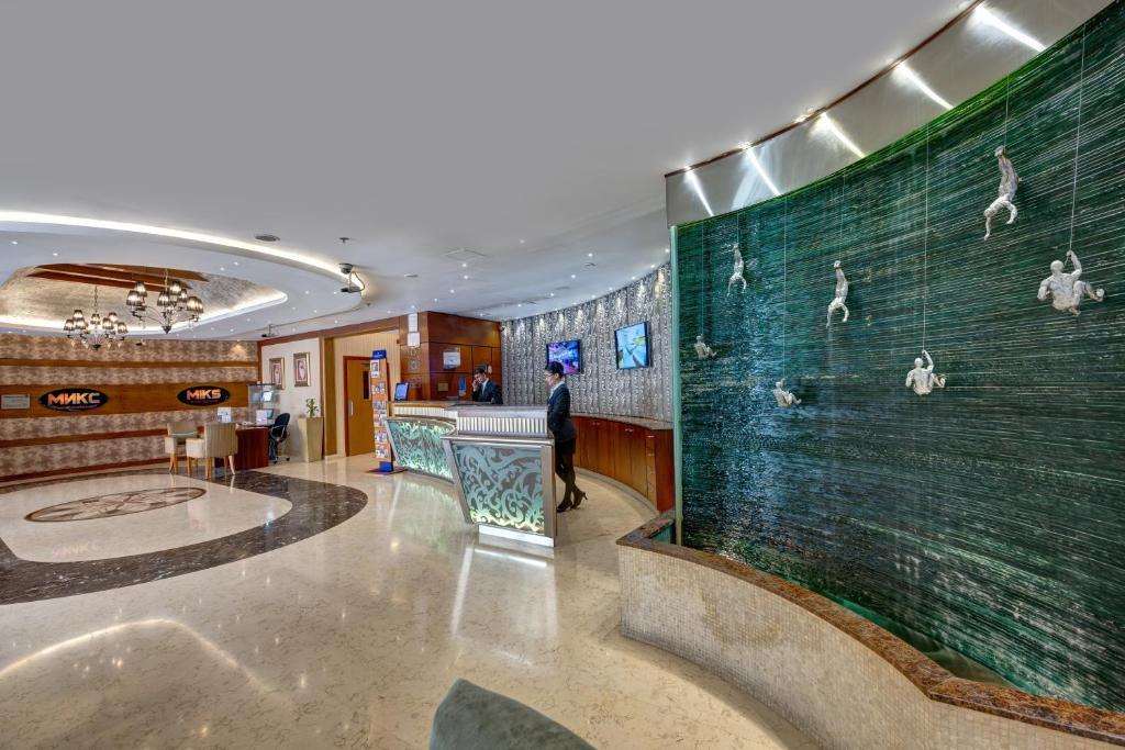 a man walking in a lobby with a wall with birds on it at Orchid Hotel Al Barsha "Formerly Golden Tulip Hotel Al Barsha" in Dubai