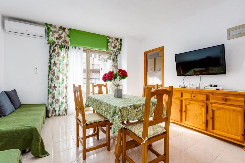 sala de estar con mesa, sillas y TV en Apartment Concordia, en Torrevieja