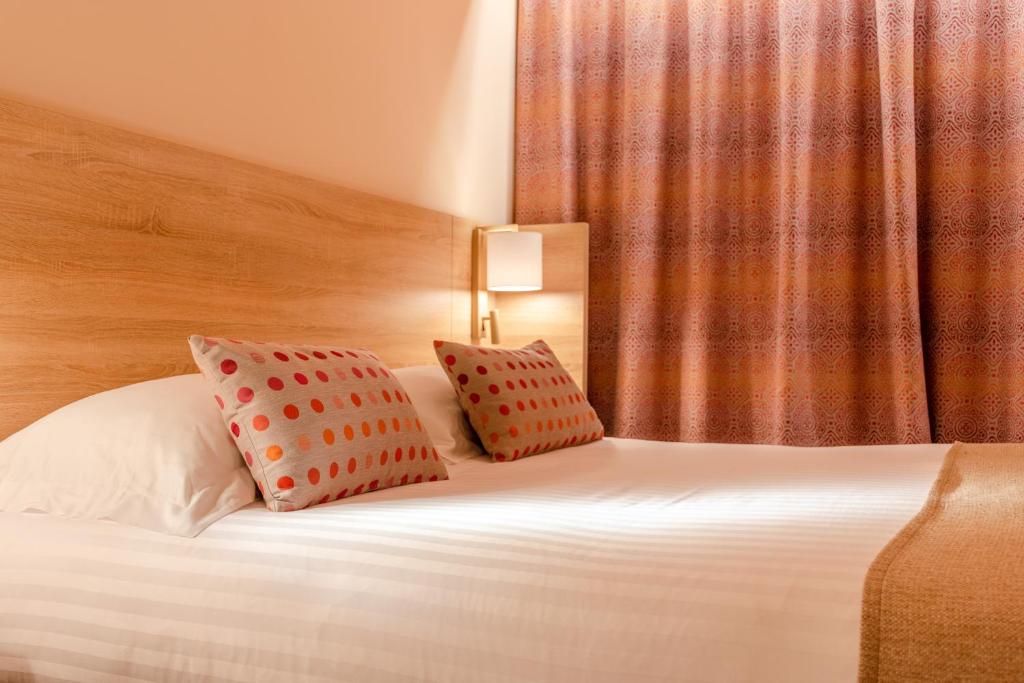 a hotel room with a bed with two pillows on it at Hôtel L'Empreinte in Cagnes-sur-Mer