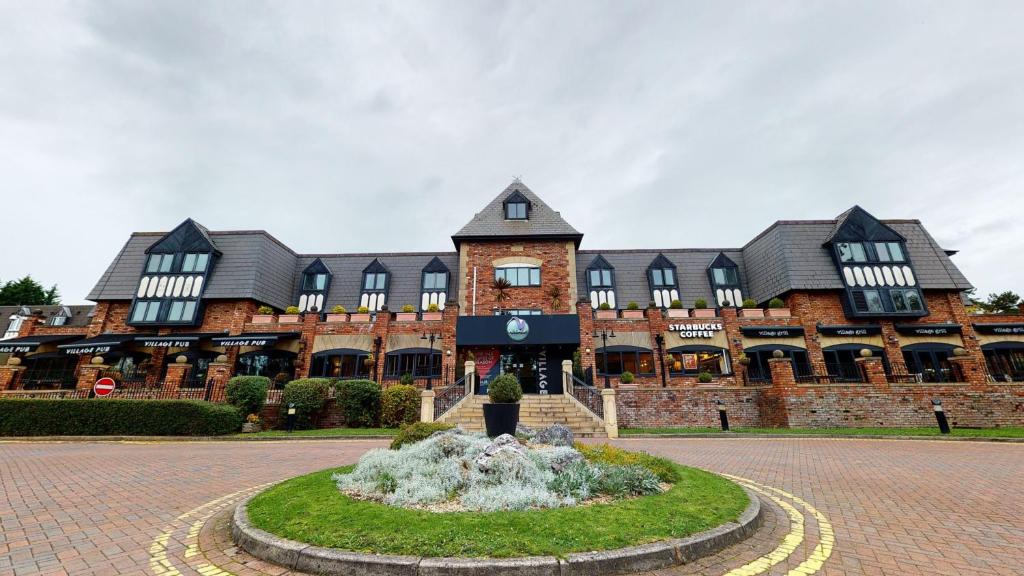 a large brick building with a clock on it at Village Hotel Manchester Cheadle in Cheadle