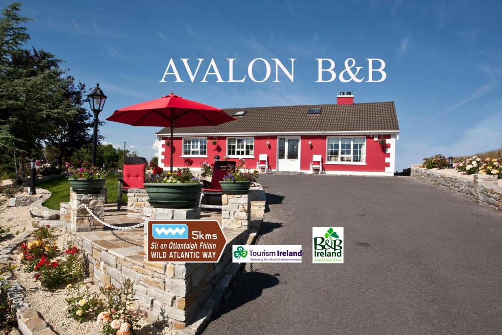 a red house with a red umbrella and a building at Avalon House B&B in Glenties