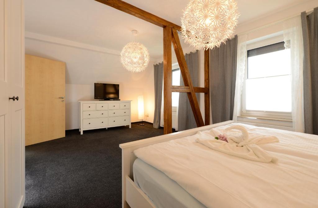 a bedroom with a white bed and a television and chandeliers at Ferienwohnung Seestern für 6 Personen mit Kamin & Terrasse in Boltenhagen