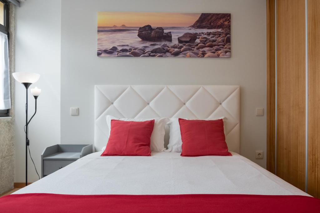 a bedroom with a large bed with red pillows at Apartamentos Portodouro - Ribeira in Porto