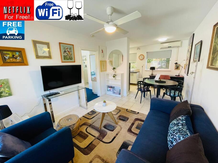 TOP LOCATION CONVENIENT QUIET WIFI NETFLIX WINE في بيرث: غرفة معيشة مع أريكة زرقاء وتلفزيون