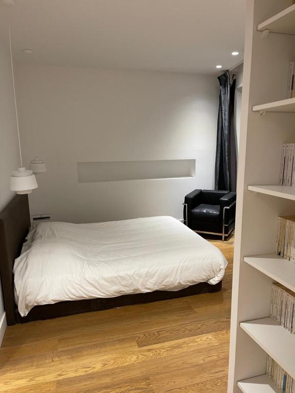 a bedroom with a white bed and a black chair at CASA GUASCO superbe duplex au cœur de la Citadelle, vue à 360 in Bastia