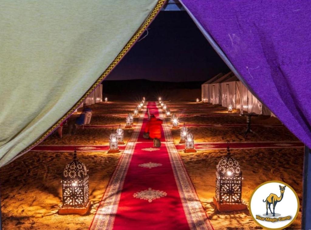 a marquee with a red carpet in a tent with lights at Your magic camp in Merzouga