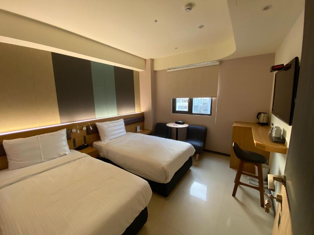 una camera d'albergo con due letti e una scrivania di Fu Kuang Hotel a Città di Pingtung