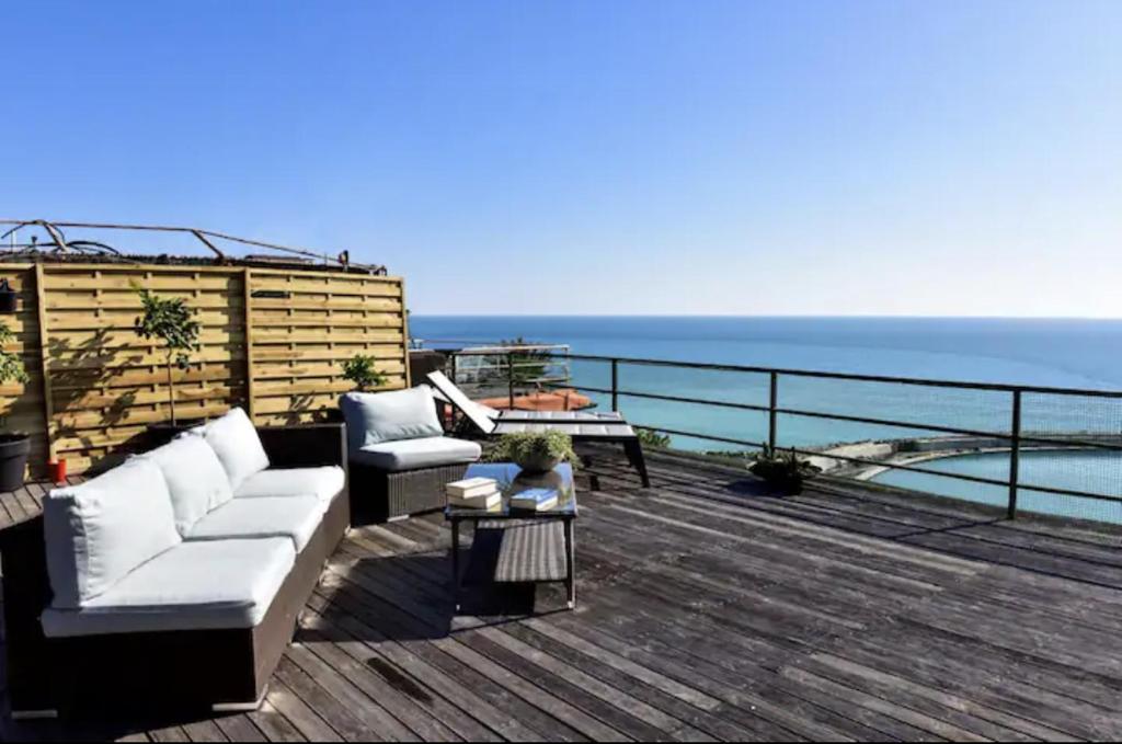 eine Terrasse mit einem Sofa und Stühlen auf einer Terrasse mit Meerblick in der Unterkunft Attico d' amare in Ventimiglia