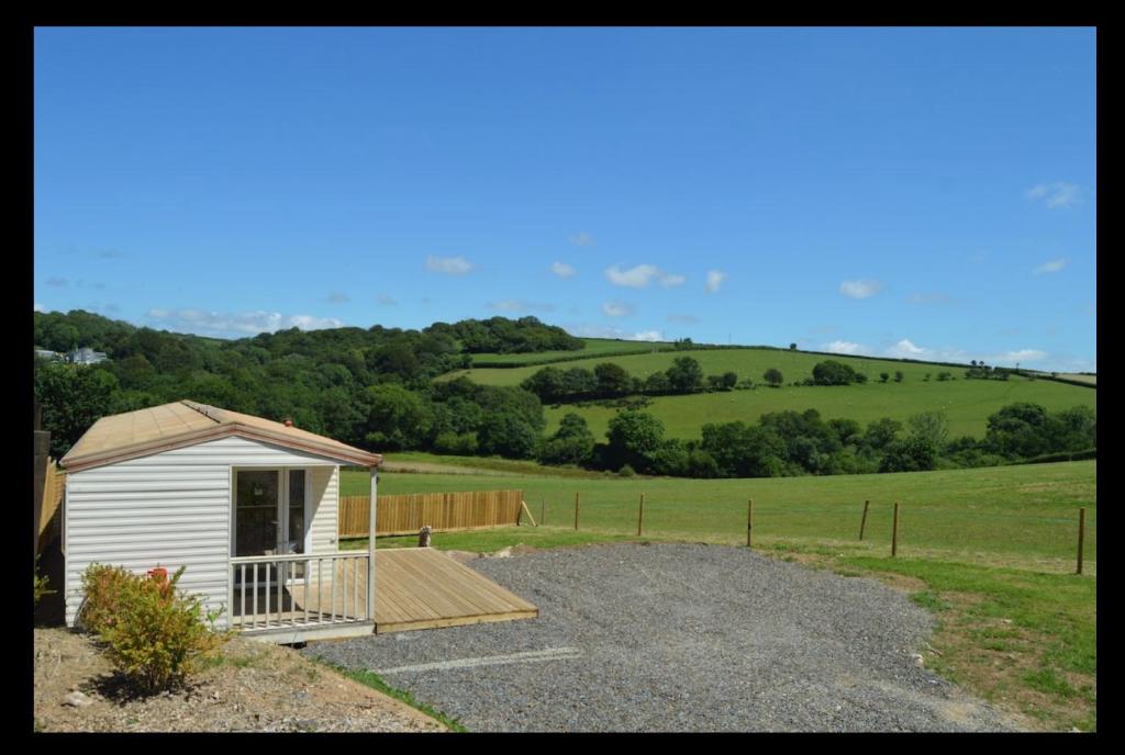 a small white shed with a porch in a field at Private country caravan surrounded by fields in Liskeard