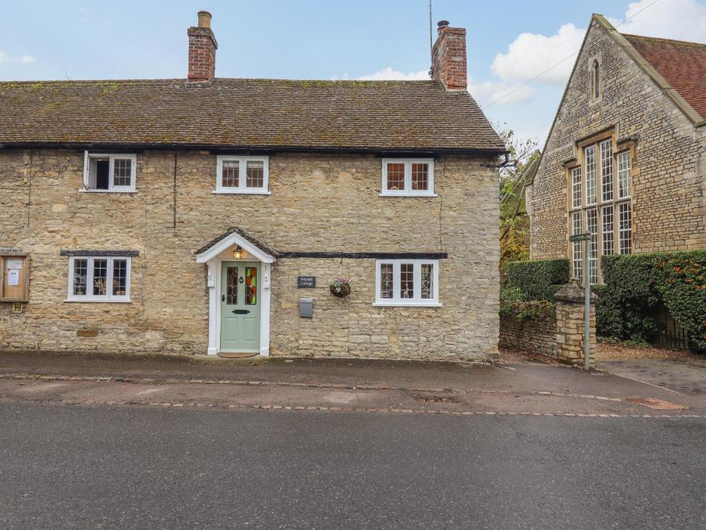 an old stone house with a green door at Wayside Cottage in Bedford