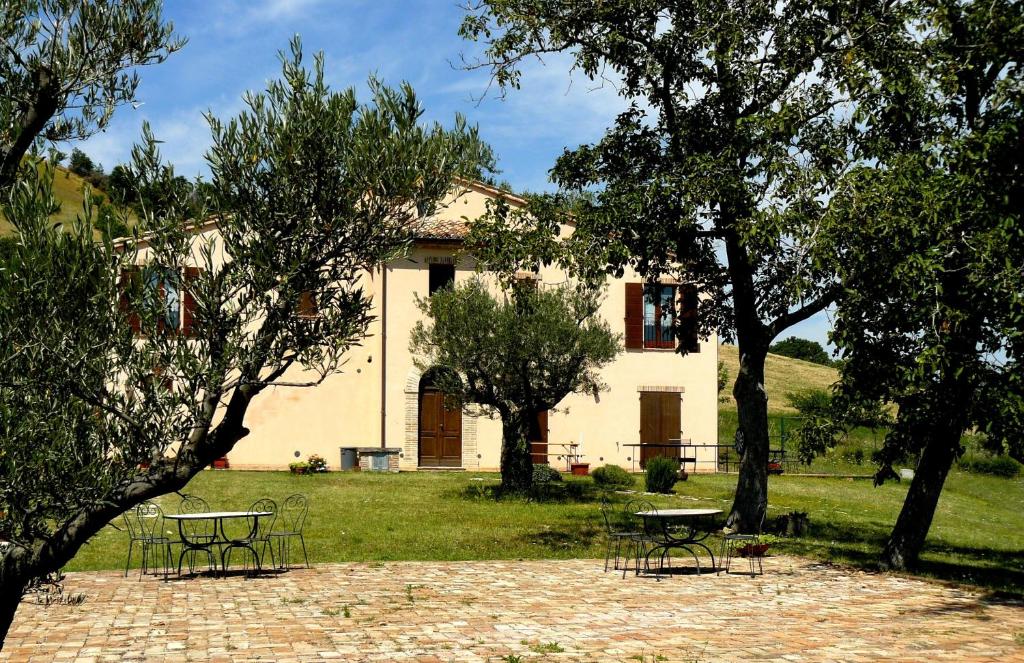 une maison avec des tables et des chaises devant elle dans l'établissement Santa Maria del Gallo, à Apiro