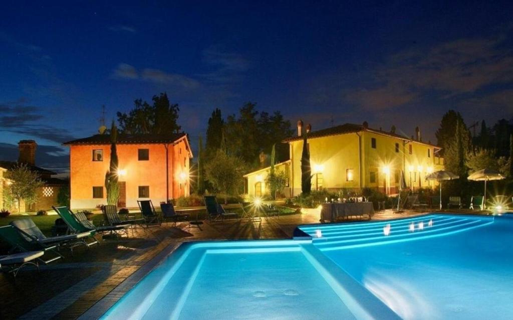 una piscina di fronte a una casa di notte di Villa Vignola a Montaione