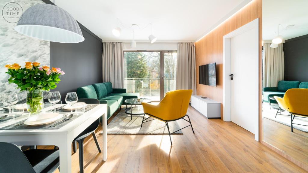 ein Wohnzimmer mit einem Tisch und gelben Stühlen in der Unterkunft Apartamenty Good Time - Stone Hill in Szklarska Poręba
