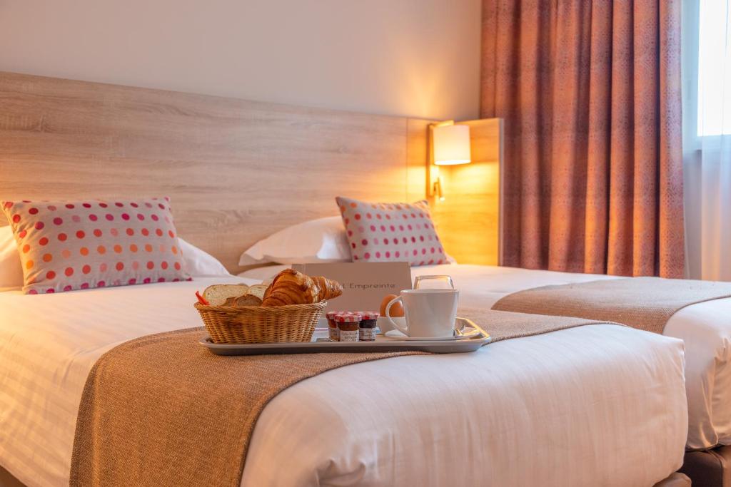 a hotel room with two beds with a tray of bread at Hôtel L'Empreinte in Cagnes-sur-Mer