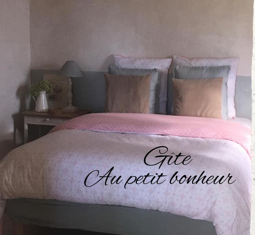 una cama con un edredón rosa con las palabras regalo a un coleccionista de mascotas en Gîte Au petit bonheur, en Châteldon