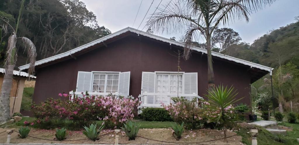 une petite maison rouge avec des fenêtres blanches et des fleurs dans l'établissement Casa Grande da Montanha - Sítio Pasangas, à Santo Antônio do Pinhal