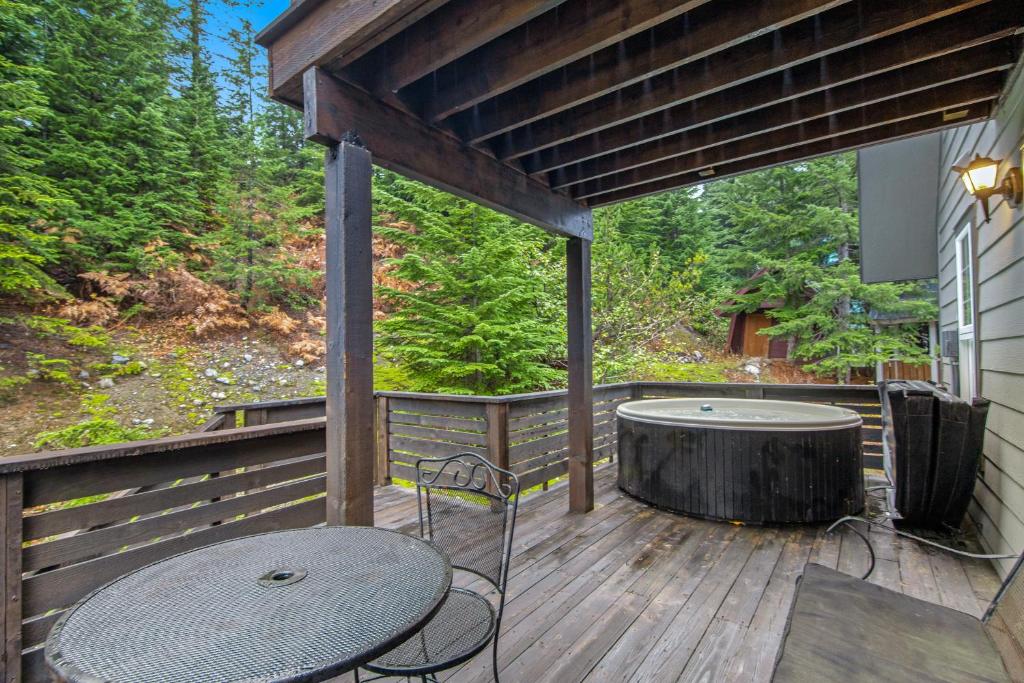 a wooden deck with a table and a tub at Black Diamond Cabin in Snoqualmie Pass