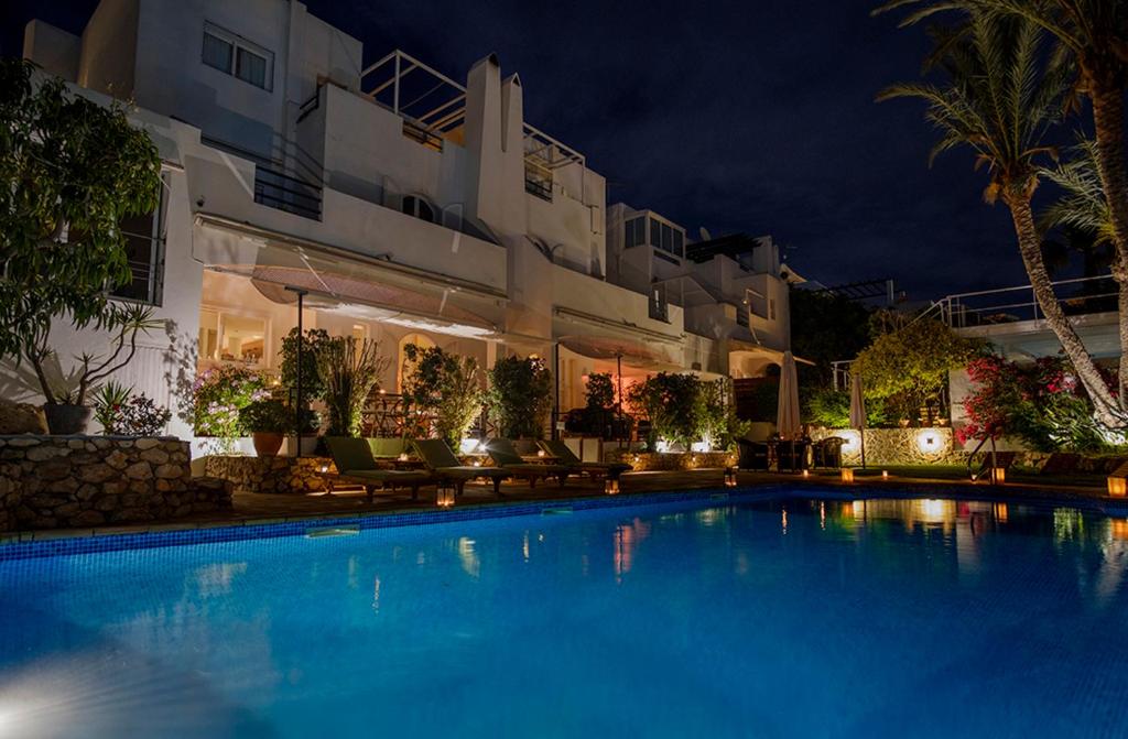 a swimming pool in front of a hotel at night at miKasa Agua Amarga & SPA in Agua Amarga
