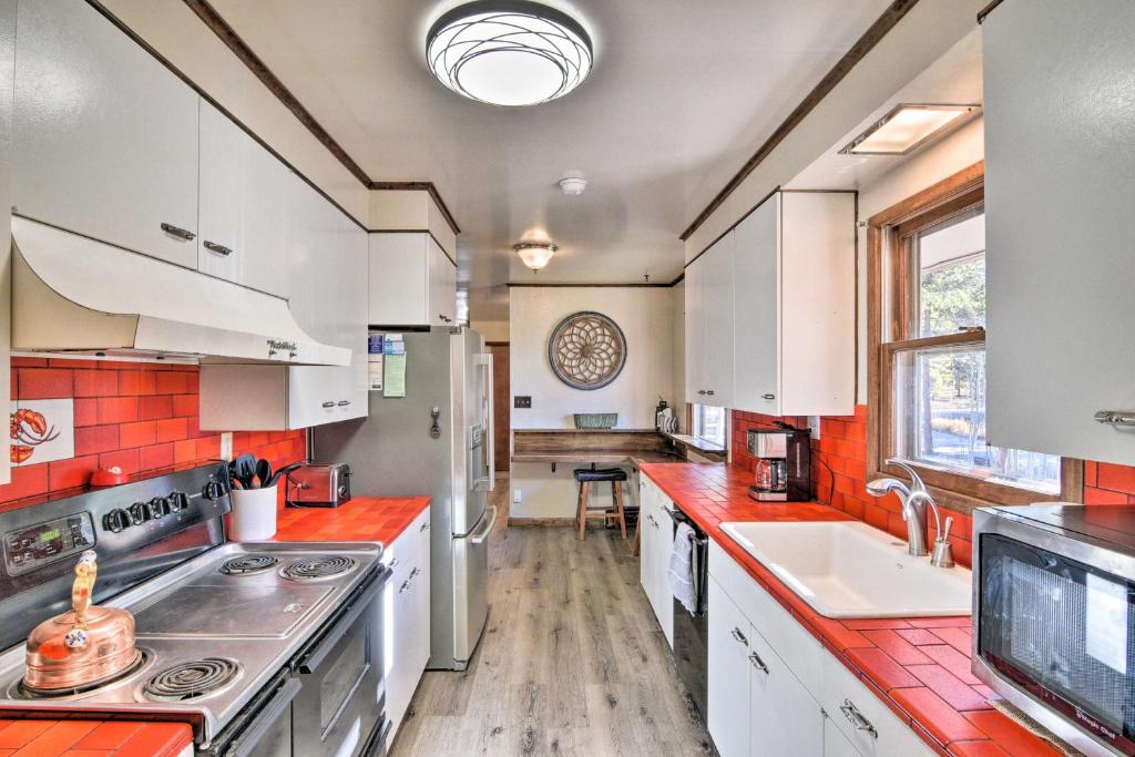a kitchen with white cabinets and red counter tops at Charming Leadville Retreat with Private Hot Tub in Leadville