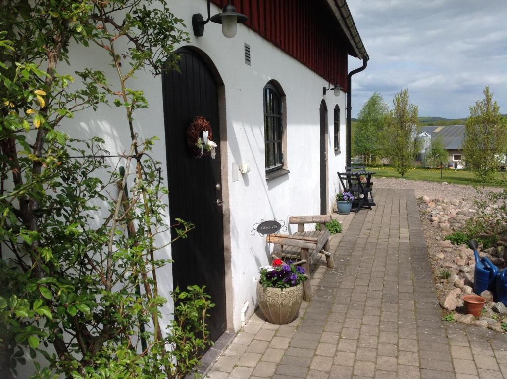a white building with a black door and a bench at Stakaberg Konferens & Gårdshotell in Halmstad