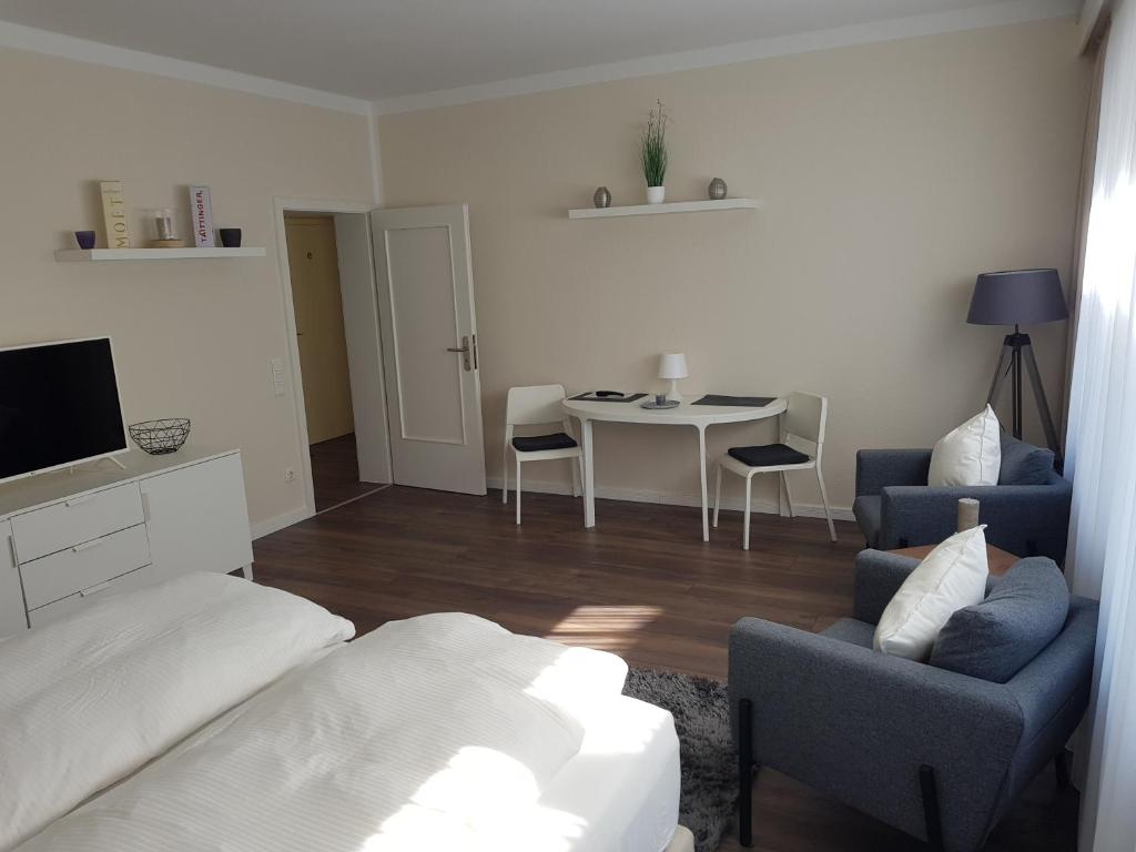 uma sala de estar com uma cama e uma mesa com cadeiras em City Apartments em Krefeld