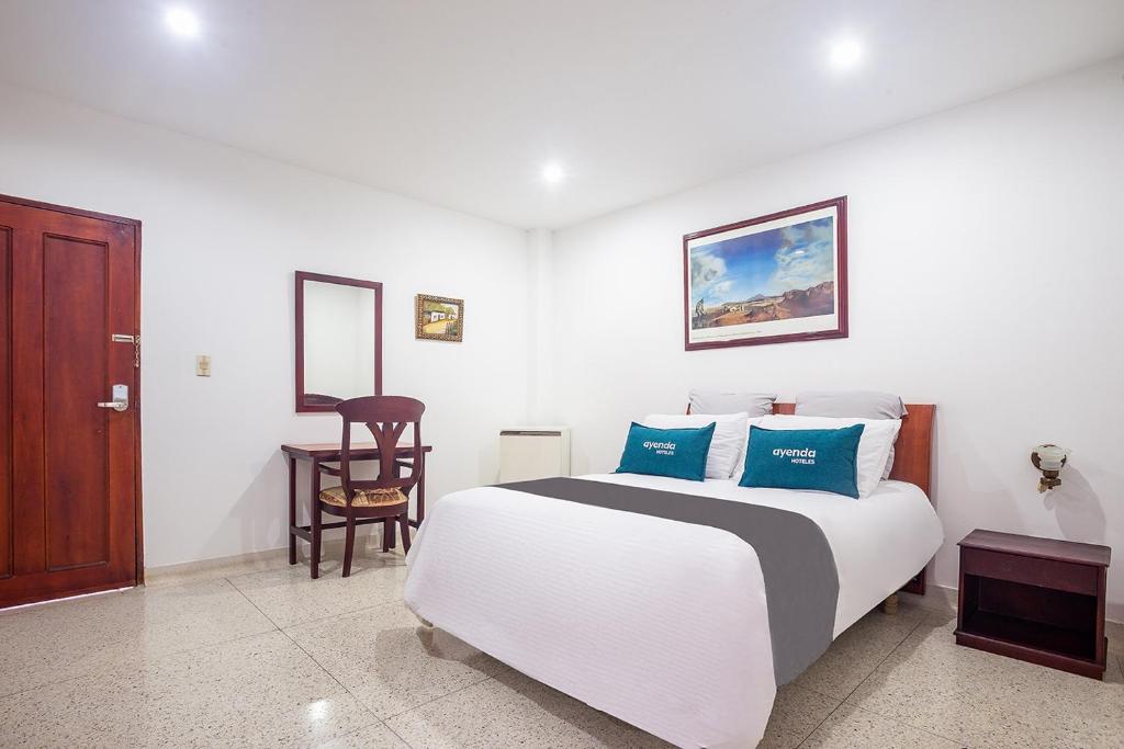 a bedroom with a white bed with blue pillows at Ayenda Hotel Carivdi in Sincelejo