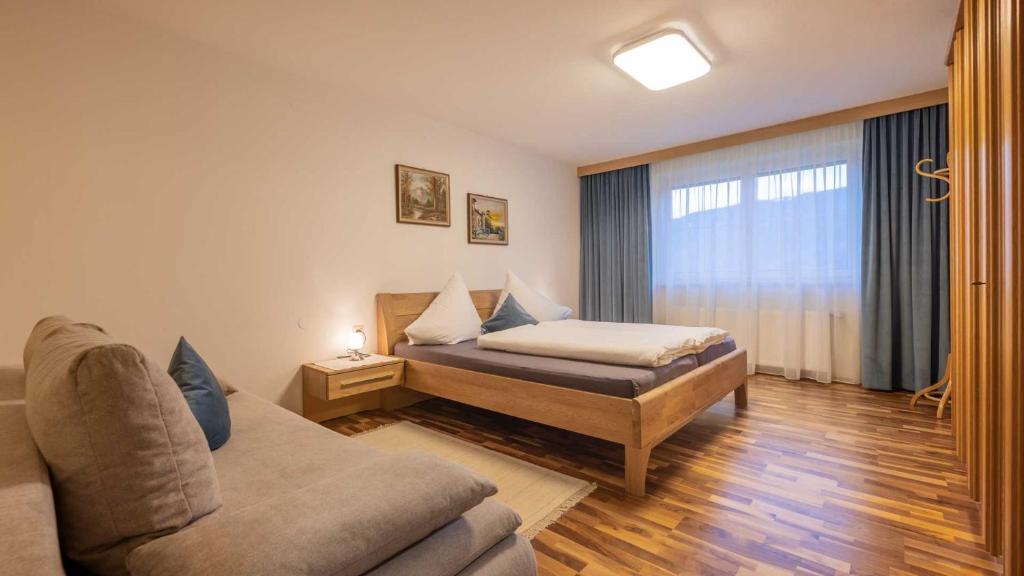a bedroom with a bed and a couch and a window at Haus Auer Theresia in Telfes im Stubai