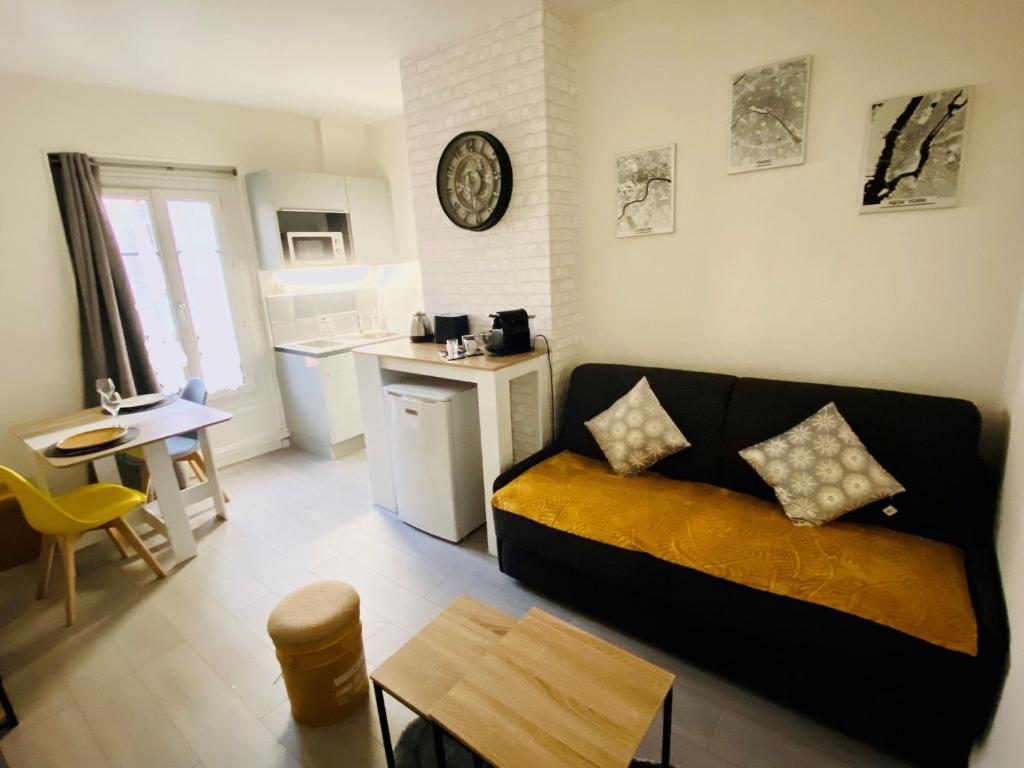 uma sala de estar com um sofá e uma cozinha em ENGHIEN-LES-BAINS: studio au cœur du centre ville. em Enghien-les-Bains