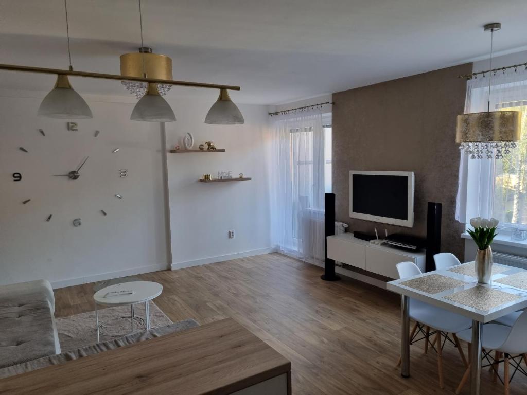 a living room with a table and a clock on the wall at VIP apartmán in Rajecké Teplice
