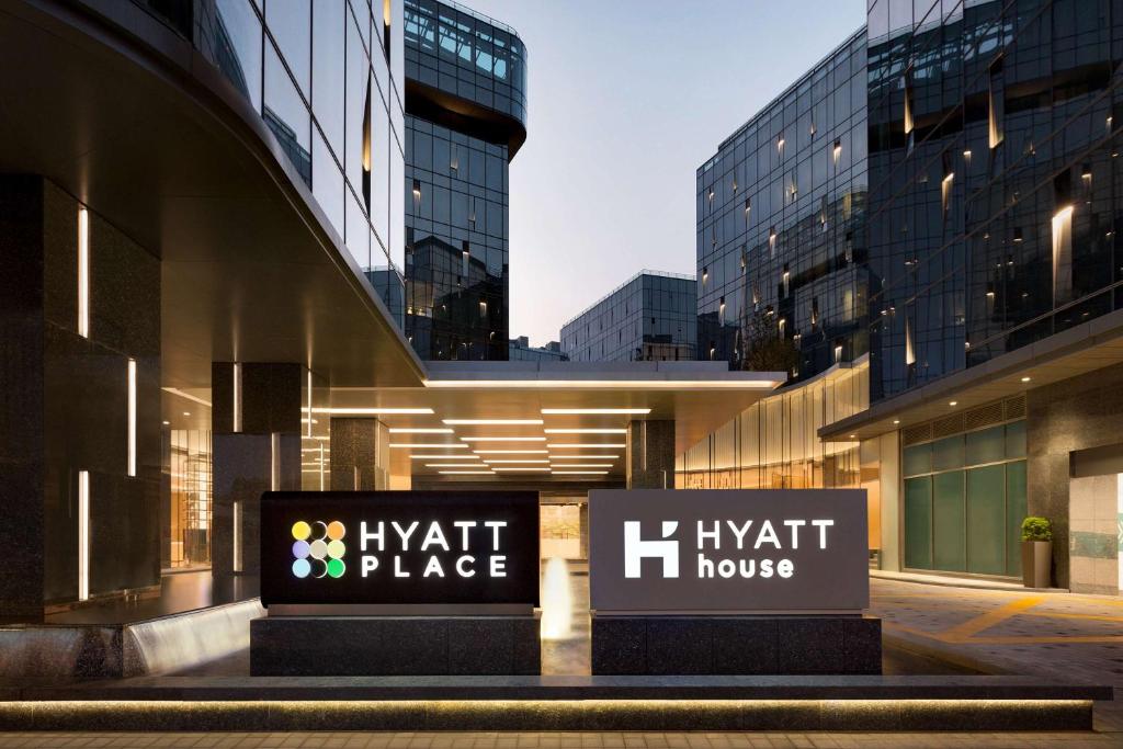 two signs in front of a building with buildings at Hyatt Place Shanghai Hongqiao CBD in Shanghai