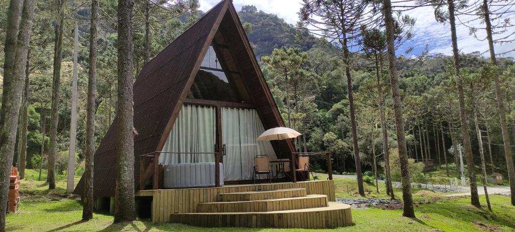 una pequeña cabaña en el bosque con escaleras y árboles en Cabanas do avencal en Urubici