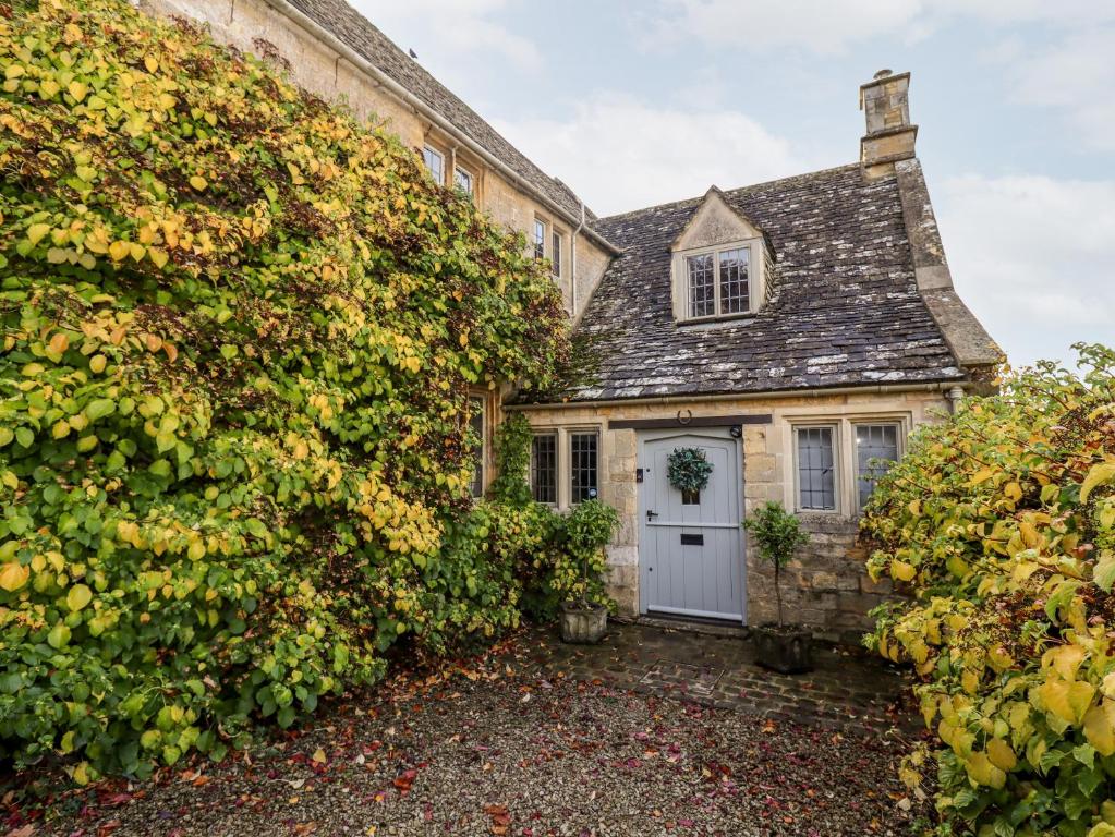 ein mit Efeu bedecktes Haus mit einer weißen Tür in der Unterkunft The Small House in Cheltenham