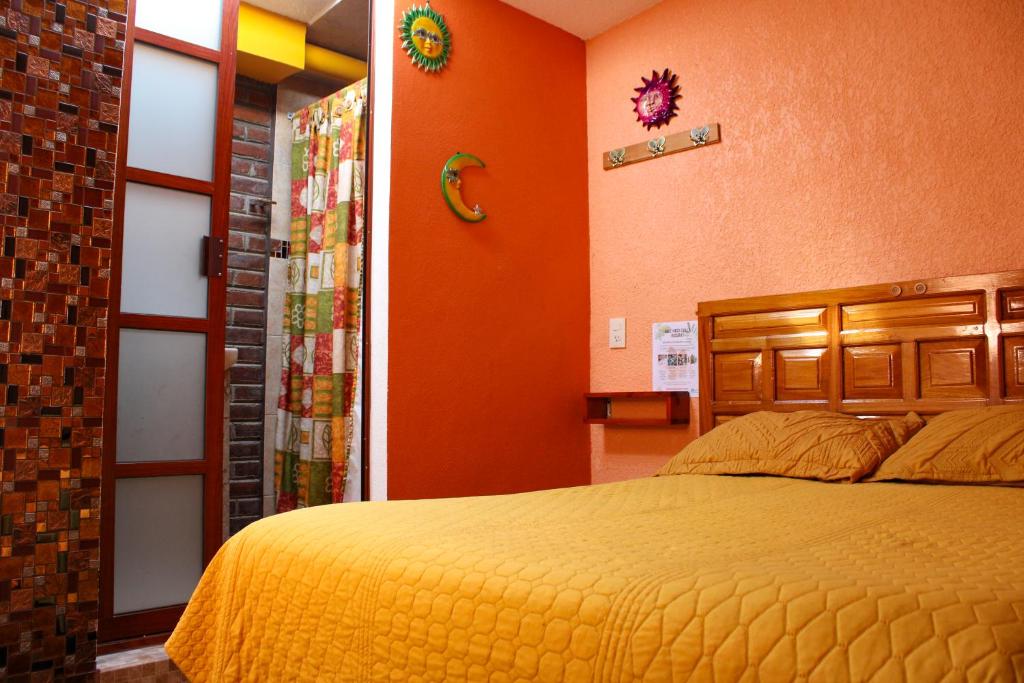 una camera con letto e parete arancione di Hospedaje Ensueño a Zacatlán