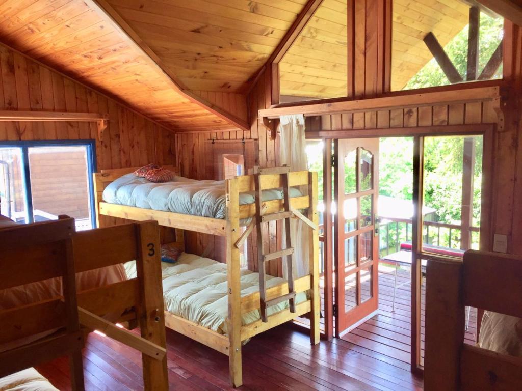 a room with two bunk beds in a cabin at Hostel Raíz in Pucón