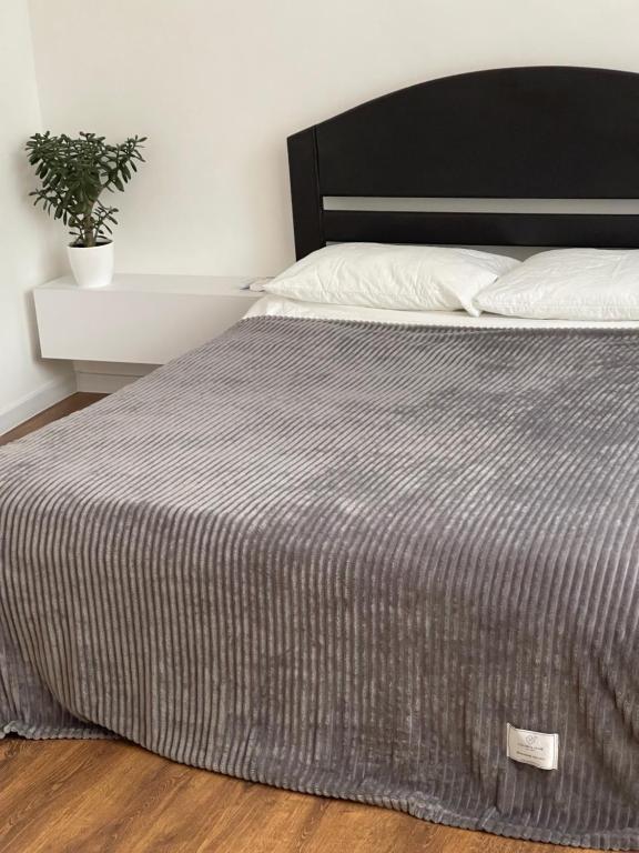una cama con una manta gris y una planta en ella en Sobornosti Apartment Poltava City, en Poltava
