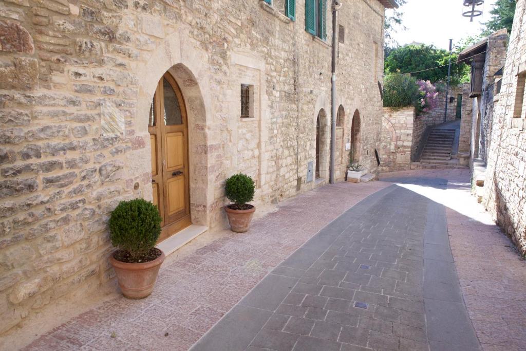 an alley with two potted plants and a wooden door at LE DIMORE ARCANGELO Giuseppe in Assisi